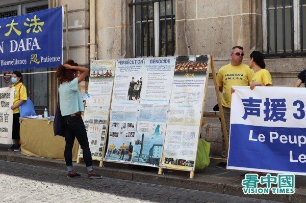 Une passante regardant le tableau d’affichage du Falun Gong. (Image : Kan Zhongguo / VisionTimes)