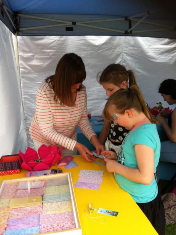 Janine apprenant aux enfants à fabriquer des fleurs de lotus en origami aux couleurs vives, lors d’un festival. (Image : Janine Rankin)